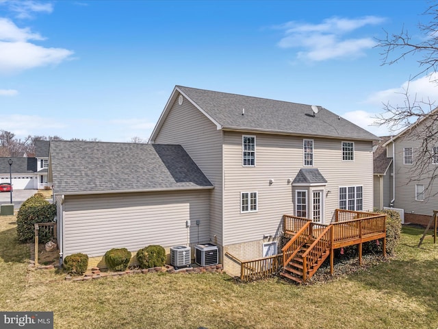 rear view of property featuring a wooden deck, central AC unit, a shingled roof, and a yard