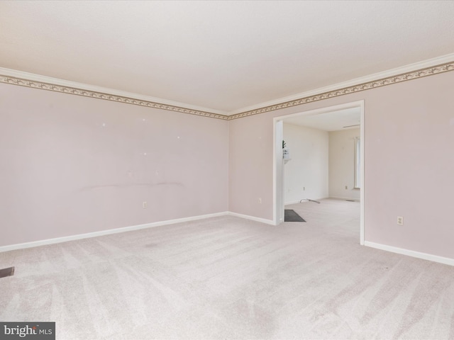 unfurnished room featuring visible vents, baseboards, light colored carpet, and ornamental molding