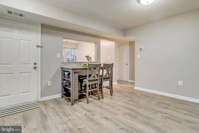 dining space with baseboards, visible vents, and light wood-type flooring