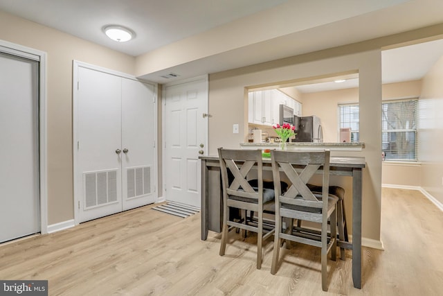 dining space featuring baseboards, visible vents, and light wood finished floors