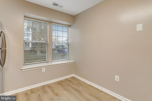 empty room with visible vents, baseboards, and wood finished floors