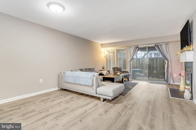 living room with baseboards, light wood-style floors, and a fireplace