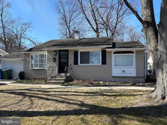 view of front facade featuring a front yard, an attached garage, brick siding, and a chimney