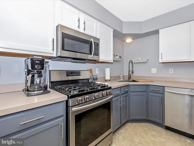 kitchen featuring white cabinetry, stainless steel appliances, light countertops, and a sink