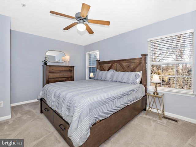 bedroom featuring light colored carpet, baseboards, and multiple windows