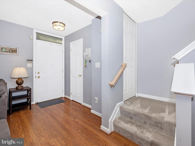 foyer with stairs, wood finished floors, and baseboards