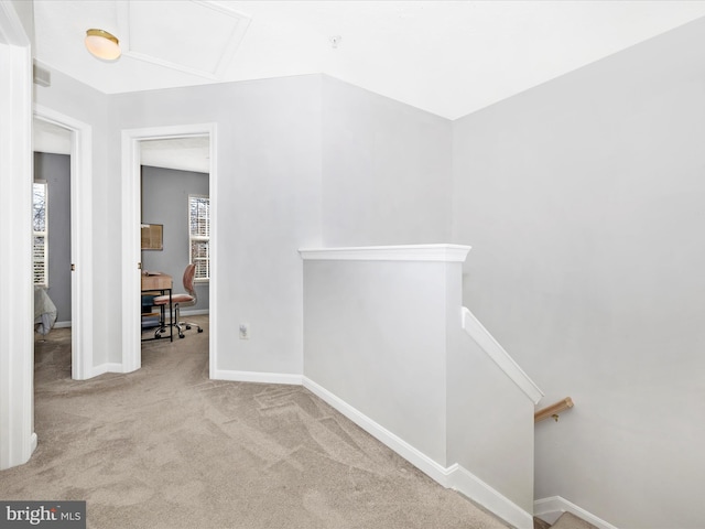 hallway with visible vents, baseboards, carpet, attic access, and an upstairs landing