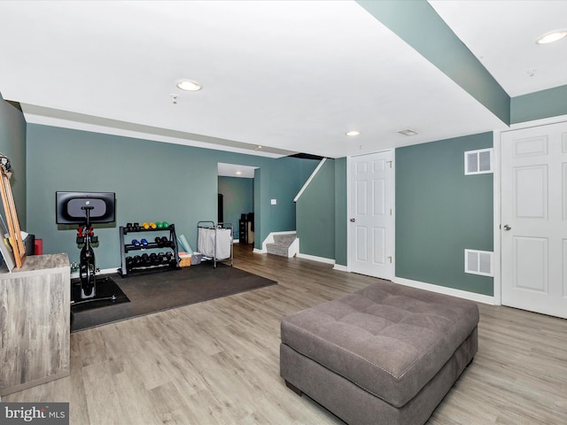 sitting room with stairway, baseboards, visible vents, and wood finished floors