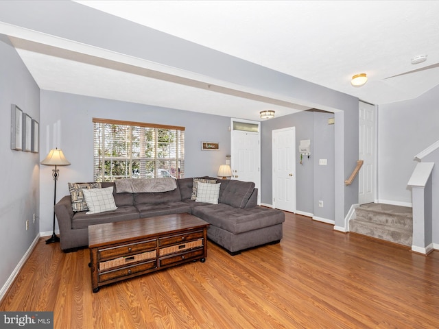 living room featuring stairway, baseboards, and wood finished floors