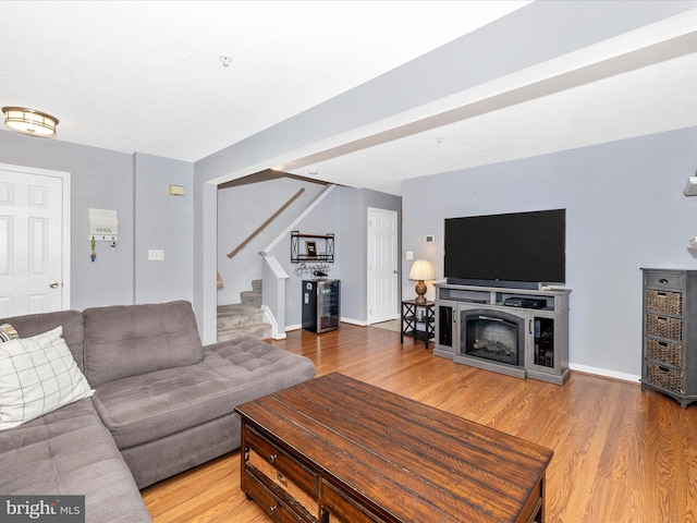 living area featuring beverage cooler, wood finished floors, stairway, a fireplace, and baseboards