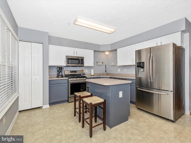 kitchen featuring a kitchen island, light countertops, appliances with stainless steel finishes, a kitchen breakfast bar, and white cabinets