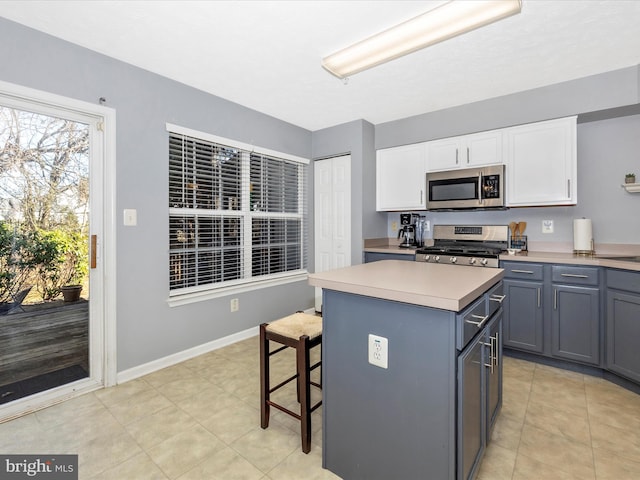 kitchen with a center island, a breakfast bar area, light countertops, white cabinets, and stainless steel appliances