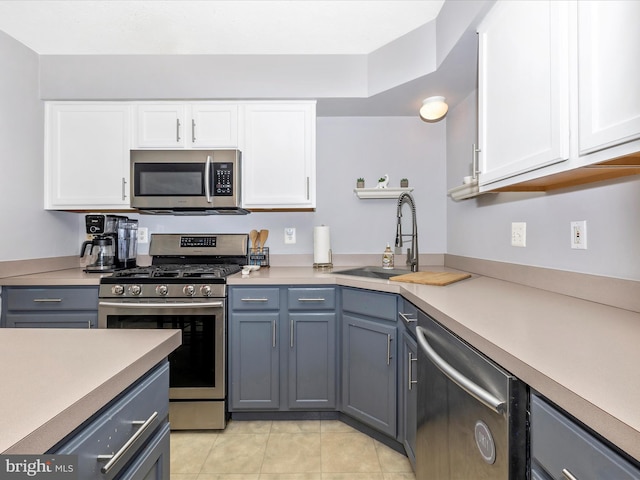 kitchen featuring gray cabinets, a sink, stainless steel appliances, white cabinets, and light countertops