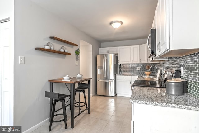 kitchen featuring decorative backsplash, light tile patterned floors, white cabinetry, and appliances with stainless steel finishes