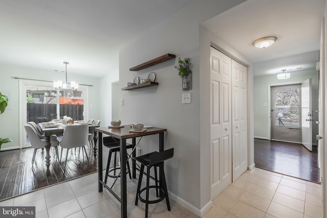 tiled dining room with baseboards and a chandelier