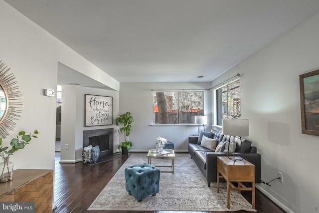 living area with baseboards, a fireplace with flush hearth, and wood finished floors