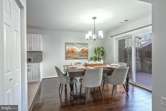 dining room featuring visible vents, baseboards, a notable chandelier, and wood finished floors