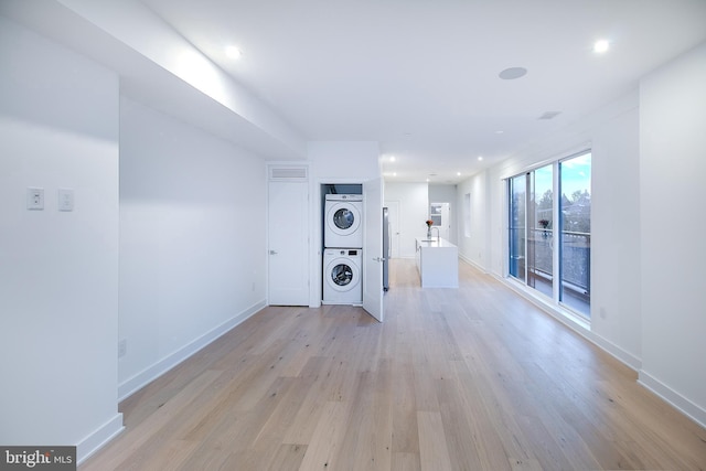 unfurnished living room with recessed lighting, baseboards, stacked washer and clothes dryer, and light wood-style flooring