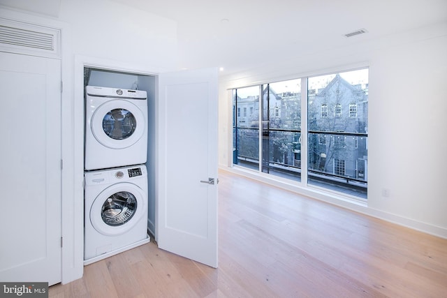 laundry room featuring light wood-style floors, stacked washer and dryer, visible vents, and laundry area