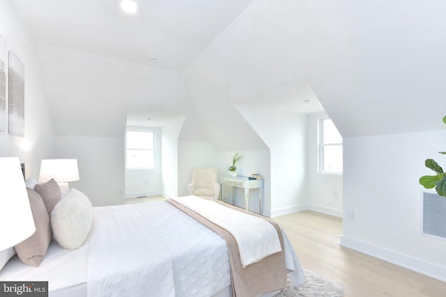 bedroom with baseboards, multiple windows, light wood-style floors, and lofted ceiling