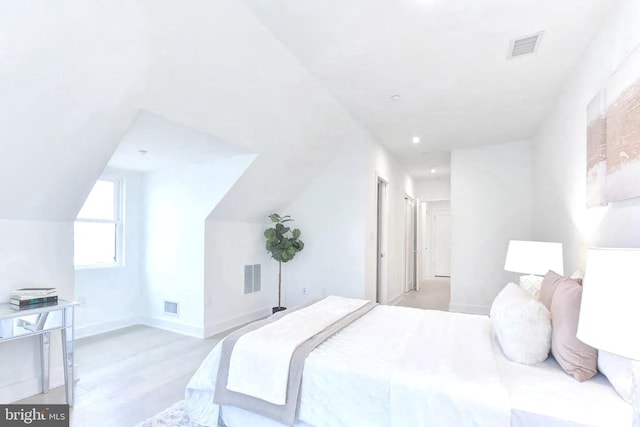 bedroom featuring visible vents, lofted ceiling, baseboards, and light wood-style flooring