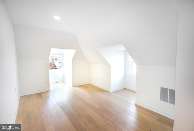 bonus room featuring visible vents, light wood-style flooring, baseboards, and vaulted ceiling