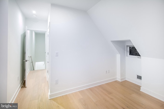 additional living space featuring visible vents, baseboards, light wood-style floors, and lofted ceiling