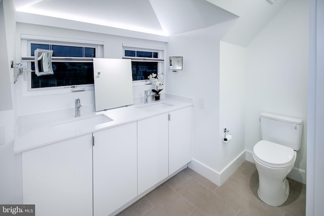 full bath featuring tile patterned floors, toilet, lofted ceiling, and a sink