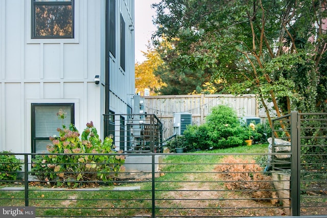 exterior space with board and batten siding, central AC, and fence