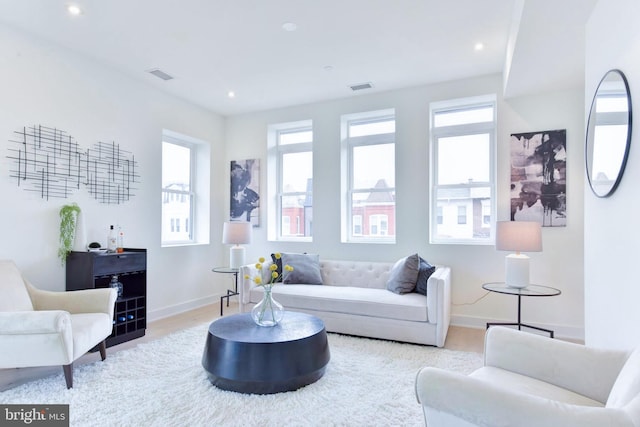 living area with recessed lighting, visible vents, baseboards, and wood finished floors