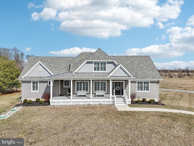 view of front of home featuring a standing seam roof, a front yard, and roof with shingles