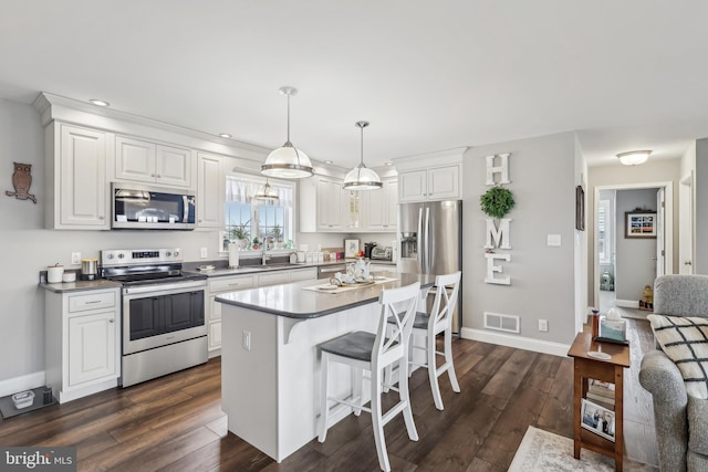 kitchen with visible vents, dark wood finished floors, a breakfast bar area, appliances with stainless steel finishes, and a sink