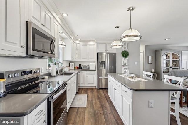 kitchen featuring a breakfast bar, dark wood-style flooring, a sink, appliances with stainless steel finishes, and white cabinetry