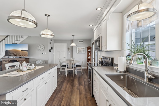 kitchen featuring visible vents, a sink, appliances with stainless steel finishes, white cabinets, and dark wood-style flooring