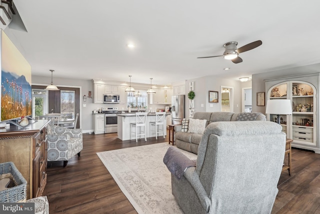 living area with recessed lighting, baseboards, a ceiling fan, and dark wood-style flooring