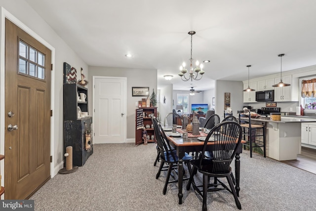 dining room with ceiling fan with notable chandelier, baseboards, and carpet floors