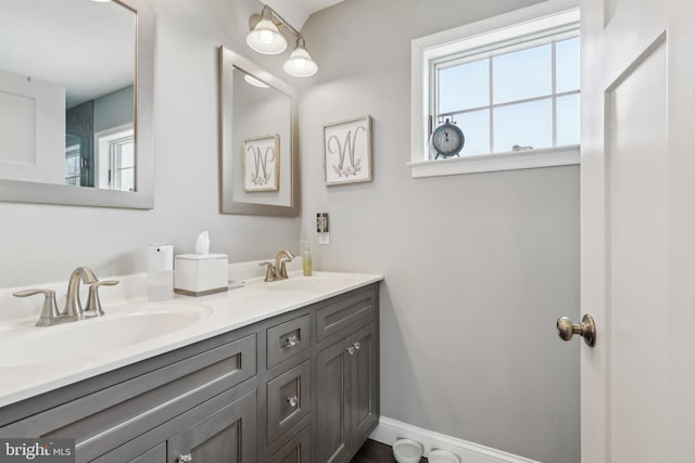 full bathroom with double vanity, baseboards, and a sink