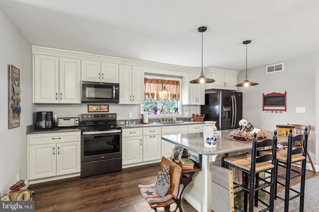 kitchen featuring visible vents, dark wood-type flooring, stainless steel appliances, white cabinetry, and a sink