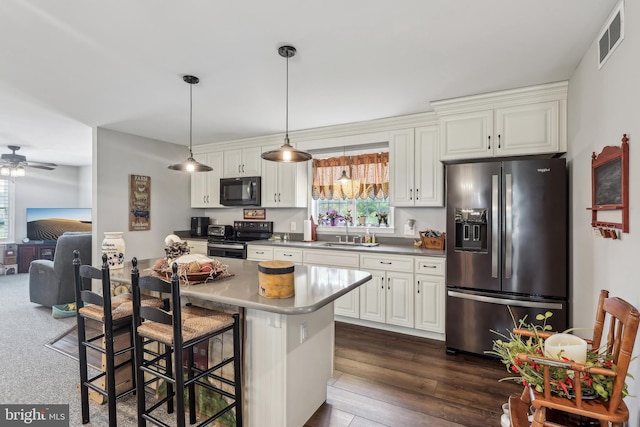 kitchen featuring visible vents, ceiling fan, a kitchen bar, stainless steel appliances, and a sink