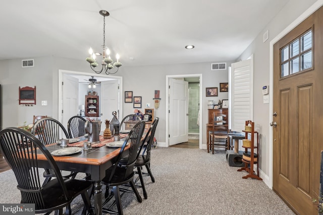 carpeted dining area featuring ceiling fan with notable chandelier, visible vents, and baseboards