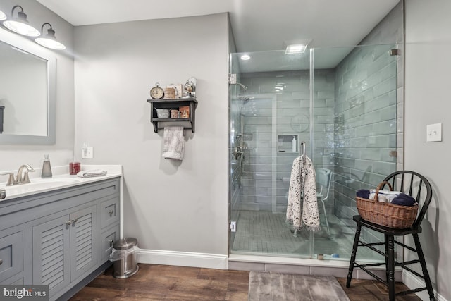 full bathroom featuring vanity, a shower stall, wood finished floors, and baseboards