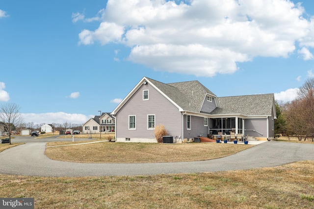 view of front facade with cooling unit, driveway, a front lawn, and a sunroom