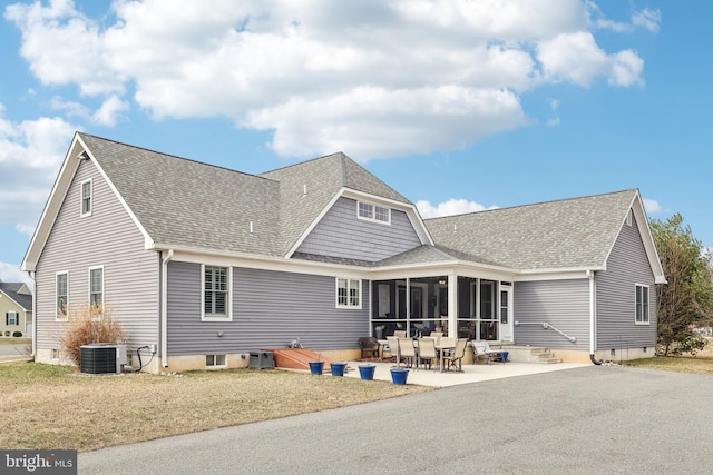 back of house with a patio area, central AC unit, a shingled roof, and a sunroom