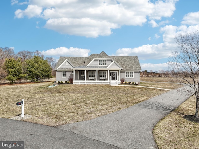 shingle-style home with a front lawn, aphalt driveway, covered porch, metal roof, and a standing seam roof