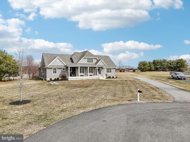 shingle-style home with a front lawn, a porch, metal roof, driveway, and a standing seam roof