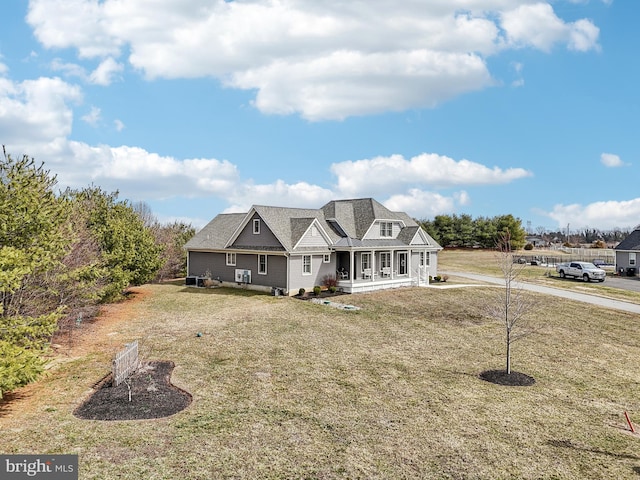 shingle-style home featuring covered porch and a front lawn