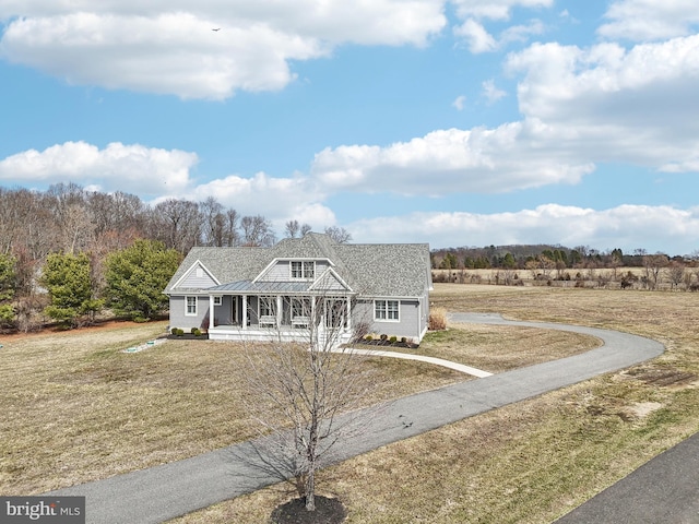 view of front of home with a front yard, covered porch, and driveway