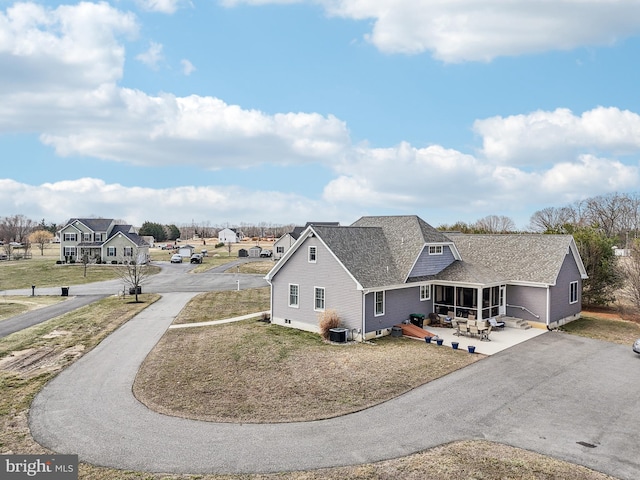 exterior space featuring aphalt driveway, cooling unit, a patio, and a sunroom