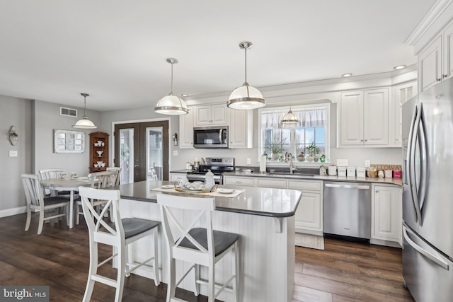 kitchen with a breakfast bar area, a sink, stainless steel appliances, dark wood-type flooring, and white cabinetry