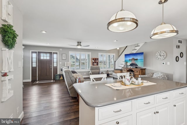 kitchen with visible vents, dark wood finished floors, open floor plan, decorative light fixtures, and white cabinetry